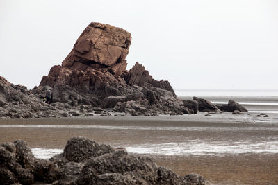 Rocks on calm beach against clear sky