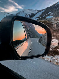 Reflection of mountains during sunset on side-view mirror of car