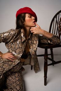 Young woman with chair against gray background