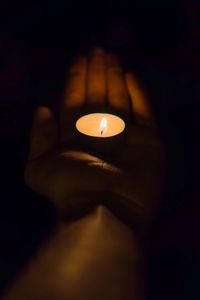 Close-up of lit candle in the dark