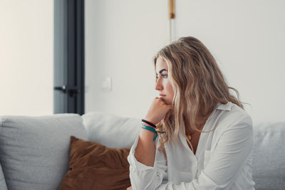 Young woman looking away while sitting at home