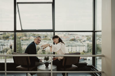 Smiling male and female colleagues taking selfie on smart phone at office