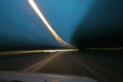 Light trails on road seen through car windshield at night