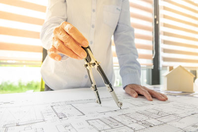 Midsection of female architect working on blueprint at desk in office