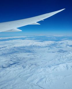 Aerial view of airplane wing over snow covered landscape