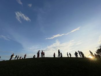 Silhouette people at beach against sky during sunset