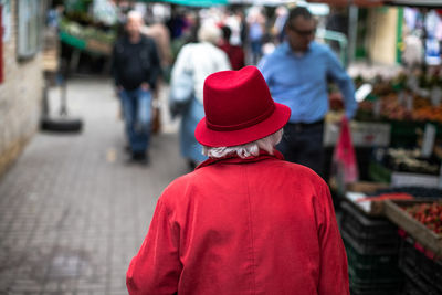 Rear view of woman wearing red clothing walking in market at city