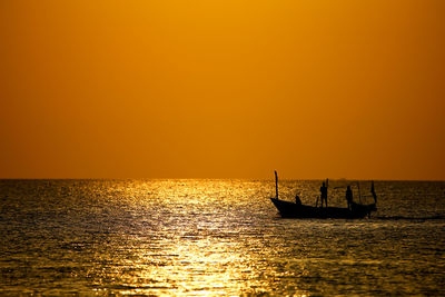 Silhouette boat in sea against orange sky