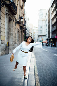 Full length portrait of woman on street in city