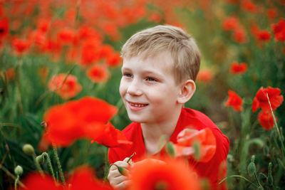 Cute smiling boy looking away against flowers