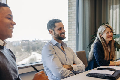 Smiling businessman with arms crossed during meeting in coworking office