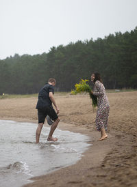 Young happy couple having fun the sea shore ar rainy summer day