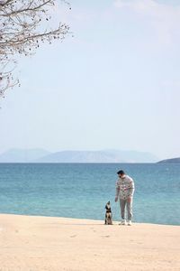 Full length of woman with dog at beach against sea and sky