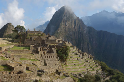 Mach picchu ruins of mountains against cloudy sky