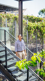 Portrait of smiling woman standing on railing