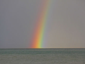 Scenic view of rainbow over sea against sky