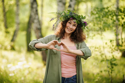 Portrait of young woman standing against trees