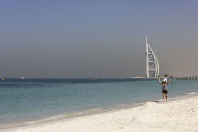 Men standing on beach against clear sky