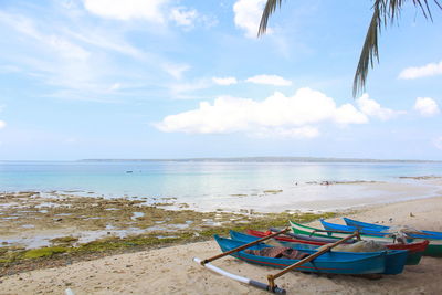 Deck chairs on beach against sky