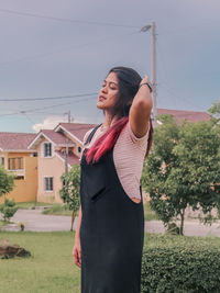 Young woman with eyes closed standing on land against sky