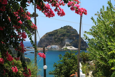 Scenic view of sea by mountain against sky