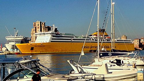 Boats moored at harbor against clear blue sky