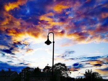 Low angle view of silhouette street light against dramatic sky