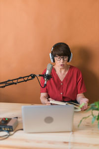 Woman reading book sitting against wall