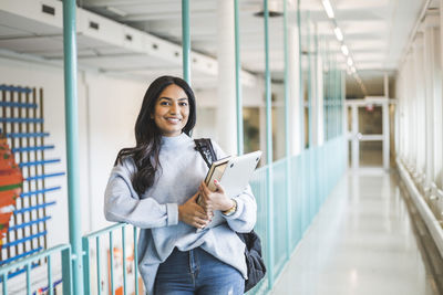 Portrait of smiling young woman standing in corridor