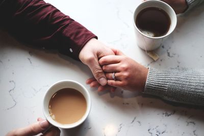 Midsection of woman holding coffee cup on table