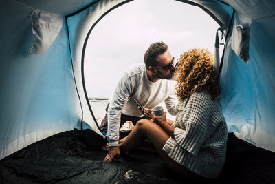 Couple kissing while sitting at tent outdoors