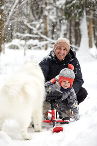 Portrait of woman with dog on snow covered field