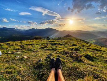 Person sitting on mountain against sky