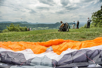 Close-up of parachute with people on mountain against sky