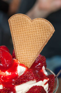 Close-up of strawberries and heart shape waffle in cup