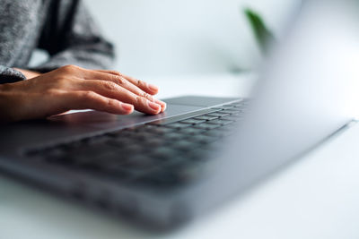 Closeup image of a woman working and touching on laptop computer touchpad on the table