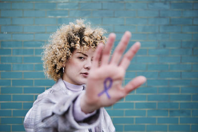 Portrait of woman with hand against wall