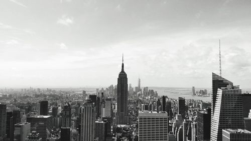 Aerial view of buildings in city against cloudy sky