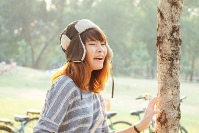 Portrait of young woman sitting on tree trunk