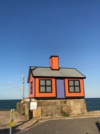 Building by sea against clear blue sky