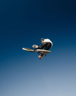 Low angle view of person jumping bicycle against sky