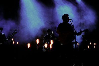 Silhouette people playing guitar at music concert