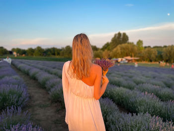 Rear view of woman standing on field against sky