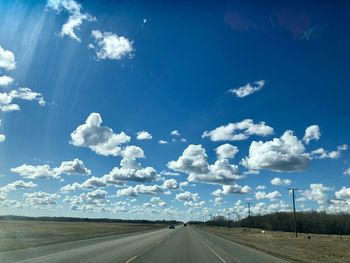 Road amidst field against sky
