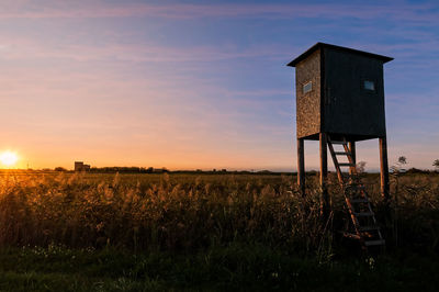 Built structure on field against sky at sunset