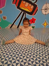 Portrait of cheerful girl sitting on patterned floor