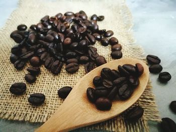 Close-up of roasted coffee beans with wooden spoon on burlap