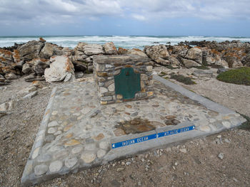 Text on rock by sea against sky