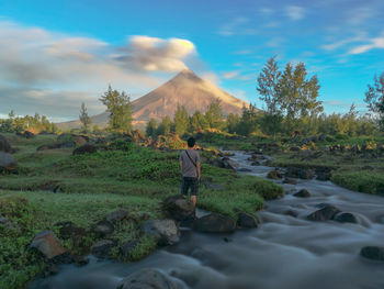 Rear view of person standing on land against sky