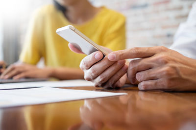 Midsection of woman using mobile phone while sitting on table